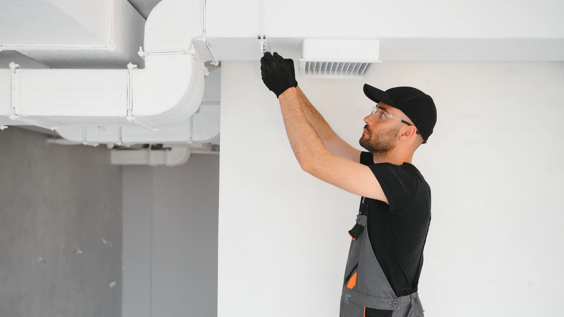 Technician replacing a filter on an overhead HVAC unit
